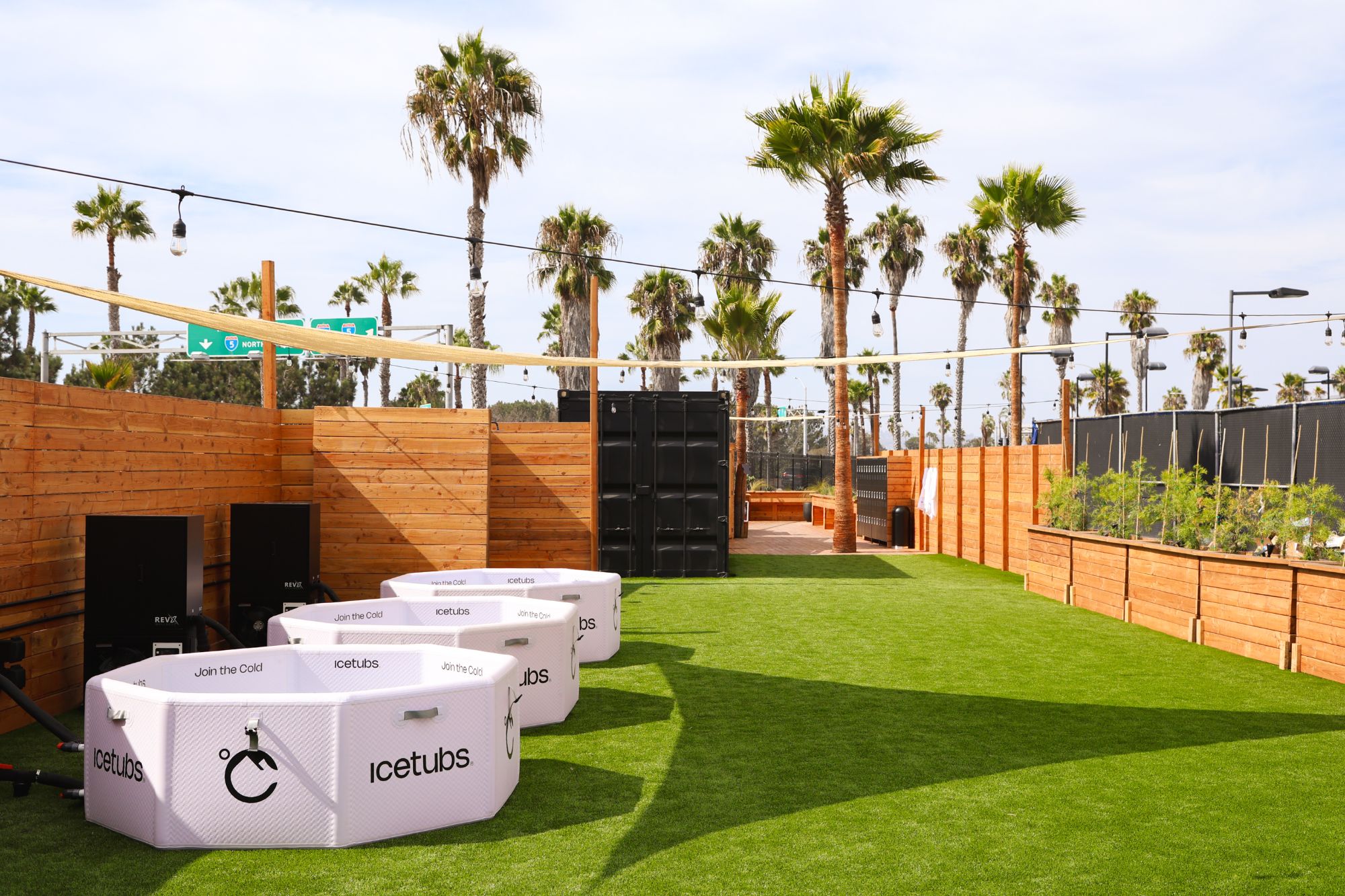 Cold plunge tubs on the lawn under palm trees at Scandinavian Heat Club