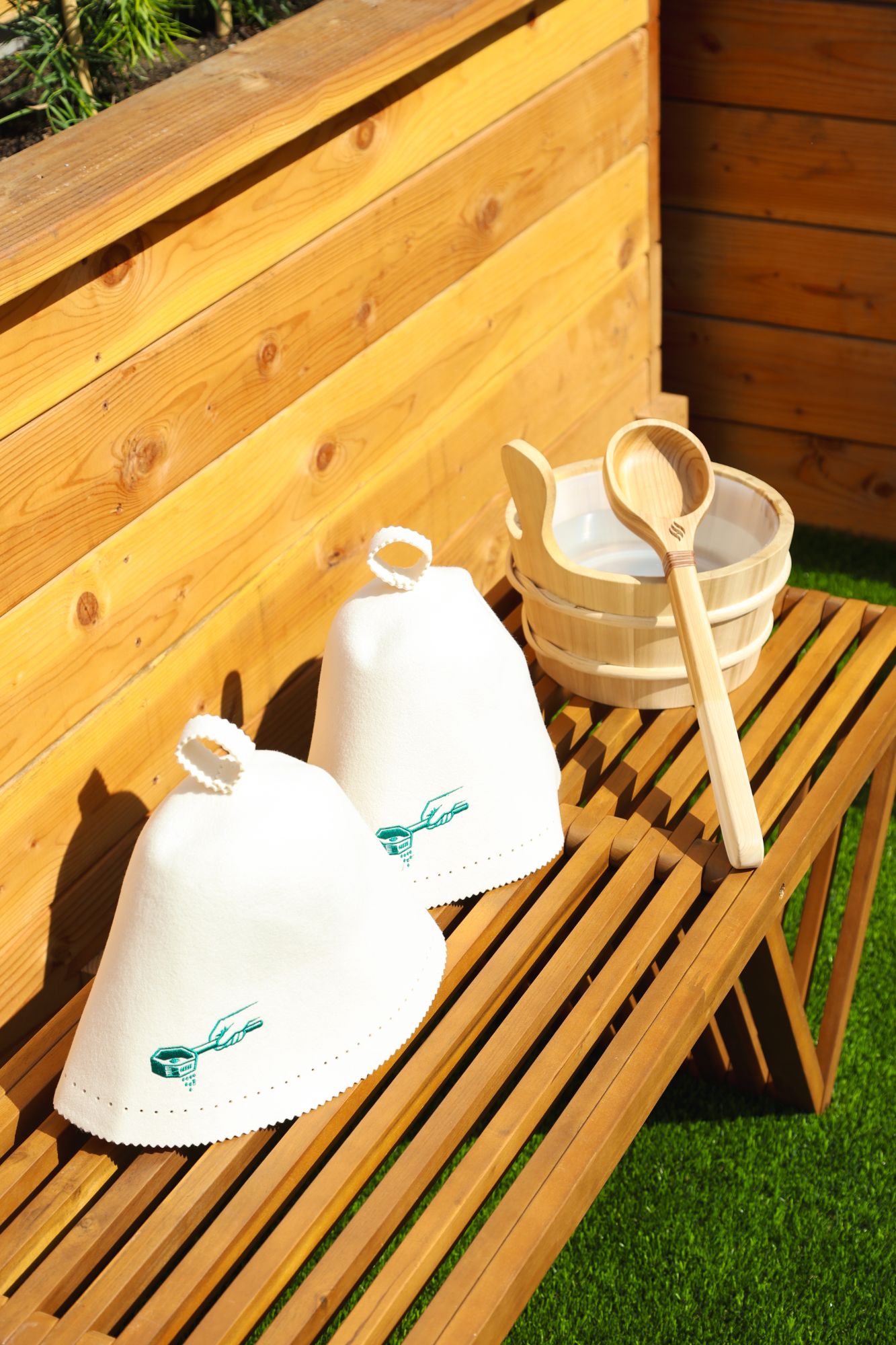 Felt sauna hats, a wooden bucket and ladle on a bench