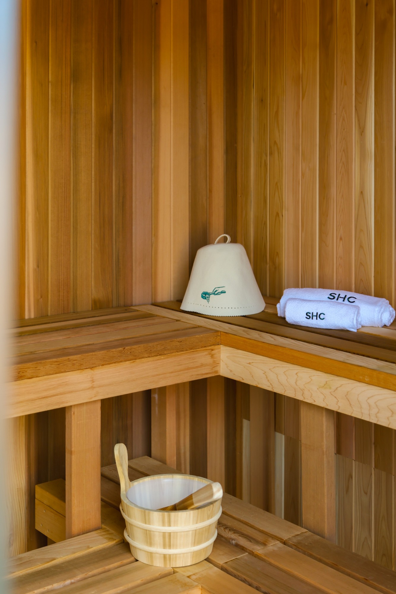 Sauna bench with a felt sauna hat, SHC towels and a wooden bucket