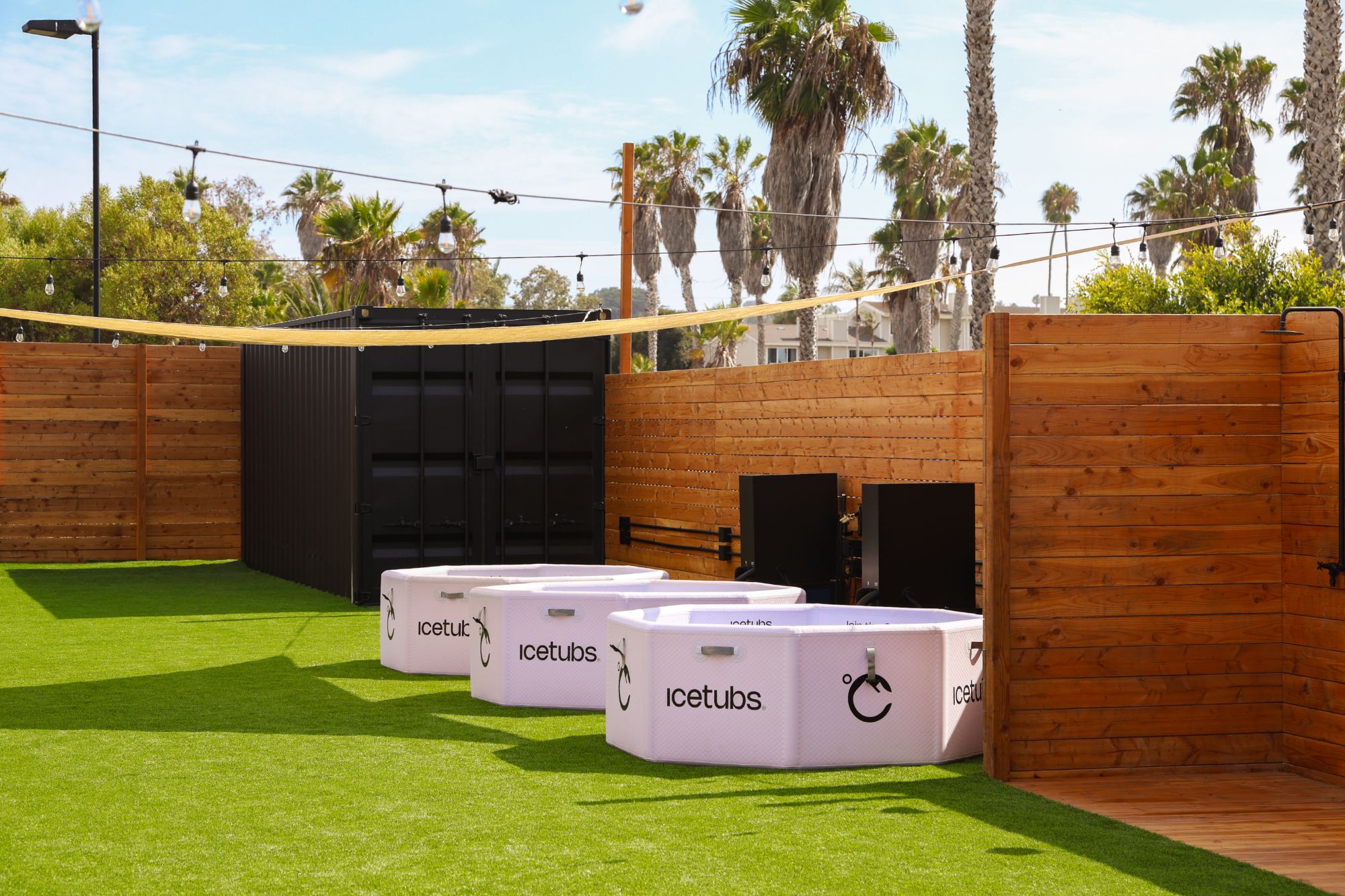 Three cold plunge tubs on the lawn beside the sauna container