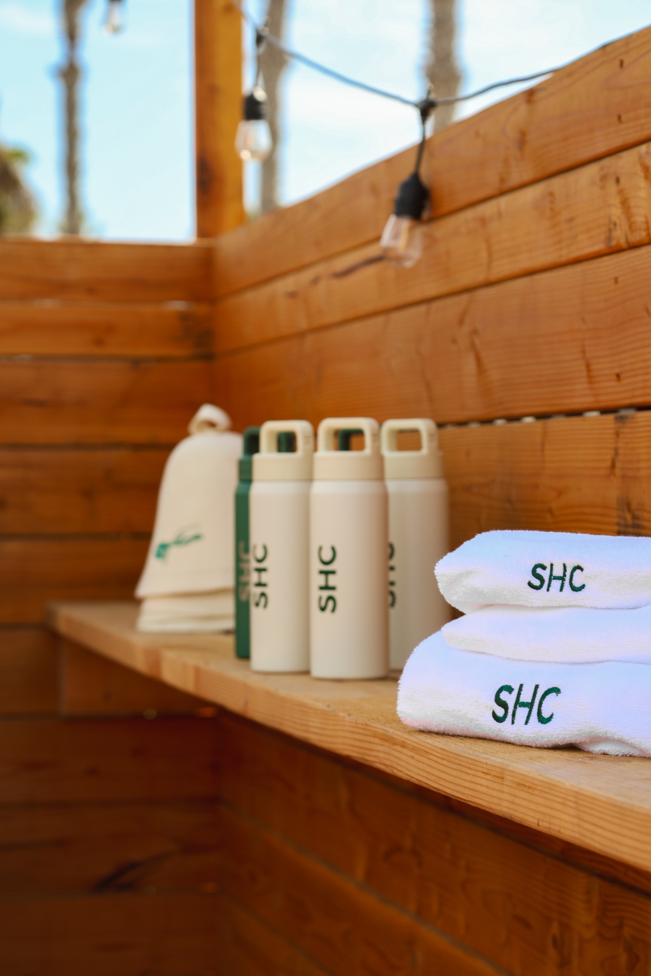 SHC water bottles and embroidered towels on a cedar shelf